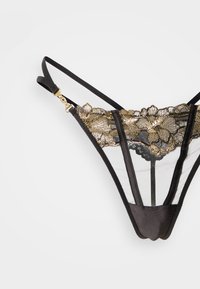 Μαύρο στρινγκ από δαντέλα με περίτεχνη χρυσή κεντημένη λουλουδάτη διακόσμηση, πάνελ από διαφανές ύφασμα και ρυθμιζόμενους ιμάντες με χρυσές μεταλλικές λεπτομέρειες.