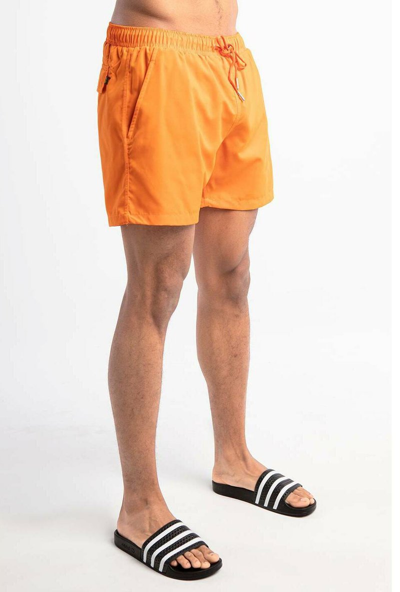 Orange Schwimmshorts mit einem elastischen Bund und Kordelzug, ausgestattet mit zwei Seitentaschen. Schwarze Slipper mit weißen Streifen.