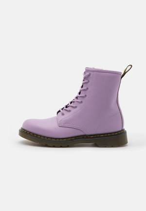 Lilla læderankelstøvle med otte snørehuller, sort sål med gule syninger og trækstrop bagpå hælen på hvid baggrund.