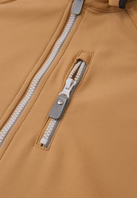 Bežová bunda na zips s hladkou textúrou látky. Obsahuje biely zips a strieborný ťahák, čím sa vyznačuje elegantným dizajnom.
