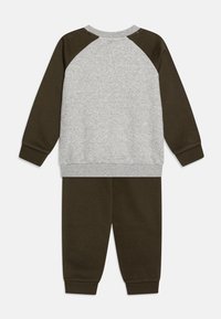 Completo a due pezzi composto da una felpa grigia in pile con maniche raglan verde scuro e pantaloni della tuta coordinati verde scuro con polsini a coste.