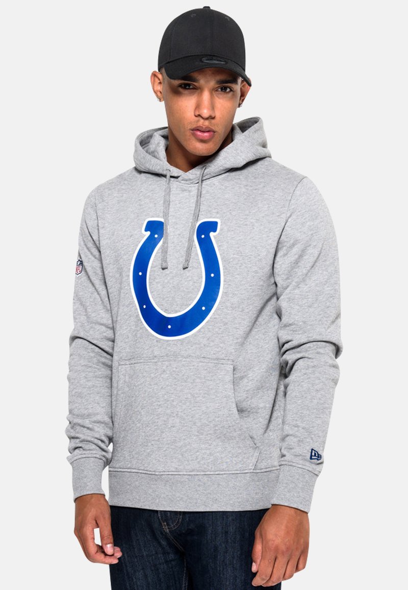 Grauer Kapuzenpulli mit einem großen blauen Indianapolis Colts-Logo auf der Vorderseite, ausgestattet mit einer Kapuze mit Kordelzug und einer Kängurutasche. Schwarze Mütze getragen.