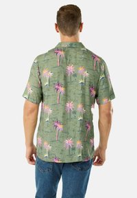 Camicetta a maniche corte con bottoni di colore verde oliva, decorata con una stampa di palme rosa e blu. Presenta un colletto e una vestibilità relax. Materiali non specificati.