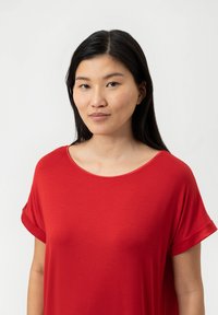 Top corto rosso a maniche corte con scollatura ampia, realizzato in tessuto morbido. Presenta risvolti e una vestibilità rilassata, mettendo in risalto un colore vivace.