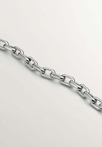 Cadena de metal en tono plateado que presenta eslabones alargados con un acabado pulido, exhibiendo una textura suave y una forma uniforme.