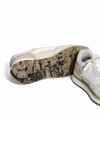 Sneaker mit einem leicht beigefarbenen Wildleder- und Mesh-Obermaterial, ausgestattet mit einer dicken weißen Zwischensohle und einer strukturierten schwarzen und braunen Außensohle mit grafischem Design.