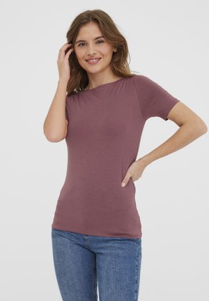 T-shirt ajusté à manches courtes en mauve discret. Fait en tissu doux et extensible avec un col rond et une texture lisse. Associé à un jean bleu.