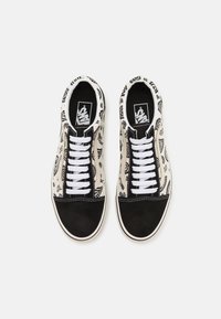 Canvas sneakers with a black and white paisley pattern, black suede toe cap, and white laces. Rubber sole and logo on the insole.