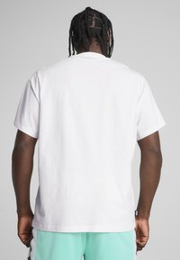 Hvid bomulds T-shirt med afslappet pasform og korte ærmer. Glat tekstur, rund halsudskæring og minimal branding ved kanten.