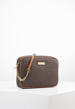 Bruine monogram crossbodytas met tan leren randje en gouden kettingriemdetail, geplaatst op een wit voetstuk tegen een effen achtergrond.