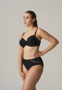 Zwart gestreepte onderwire bh en high-waisted slip set. Stof heeft een zachte textuur met kantaccenten op de bh en slip.