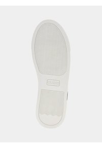 Semelle de sneaker blanche avec des motifs en zigzag texturés et un logo "GUESS" en relief. Bords lisses et légère courbure au niveau de la pointe.