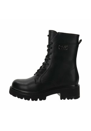Bottine noire en cuir avec un système de laçage, semelle robuste avec des crampons et un détail de tag sur le côté. Texture lisse avec une finition mate.