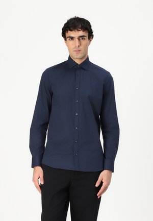 Chemise à manches longues marine avec un col boutonné, fabriquée en tissu lisse ; présente des boutons à l'avant et un design ajusté avec une silhouette élégante.