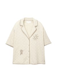Cămașă scurtă, de culoare bej deschis, cu o textură țesută, broderie decorativă cu palmieri și soare, și cusături contrastante pe margini.