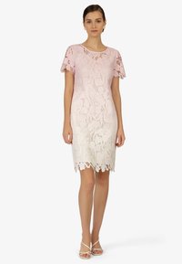 Spitzenkleid mit einem Farbverlauf von hellem Rosa zu Weiß, kurzen, schwingenden Ärmeln, gewelltem Saum und floralem Spitzenmuster. 