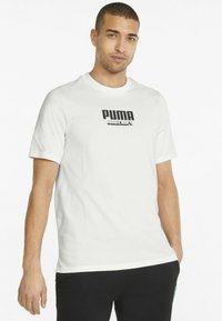 Tricou alb din bumbac, cu mâneci scurte și guler rotund, având un logo negru "PUMA" și textul "MINECRAFT" imprimate pe față.