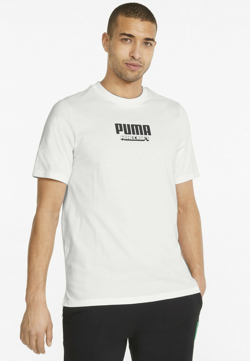 Tricou alb din bumbac, cu mâneci scurte și guler rotund, având un logo negru "PUMA" și textul "MINECRAFT" imprimate pe față.