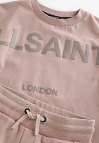 Lyserød bomulds sweatshirt og matchende joggers med hævede grå logoer med "ALLSAINTS" og "LONDON", strukturerede taljer og snore.