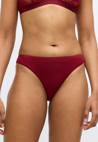 Bordowe bawełniane stringi z gładką fakturą i elastycznym pasem z logo. Posiadają minimalistyczny design i niską talię.