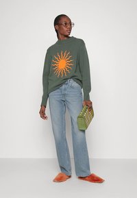 Žalias megztinis su oranžine saulės piešinėliu, šviesiai mėlynos džinsinės kelnės, oranžinės mules tipo basutės ir žalia languota rankinė. Paprastas, kasdienis derinys.