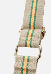 Beige canvas hihna, jossa on vihreät ja oranssit raidat, varustettuna metalliosilla. Rakenne on kudottu, ja se esittelee kestäviä ompeluyksityiskohtia.