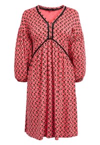 Robe rose avec un motif floral noir, encolure en V, manches bouffantes et garniture noire le long du corsage et de l'encolure.