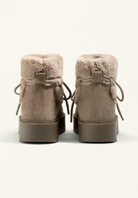 Suede ankle boots in beige with a faux fur collar, rounded toe, and textured rubber sole. Features adjustable laces and rear pull tab.