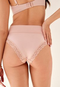 Chiloți roz cu talie înaltă, dintr-un material neted și cu un elastic moale, având margini din dantelă ca un accent delicat.