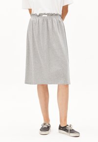 Gray, knee-length skirt made of soft material with an elastic waistband and ruffle detail. Paired with black sneakers.