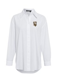 White button-up shirt with long sleeves, curved hem, collar, and a black and gold heart design on the chest. Cotton blend material.
