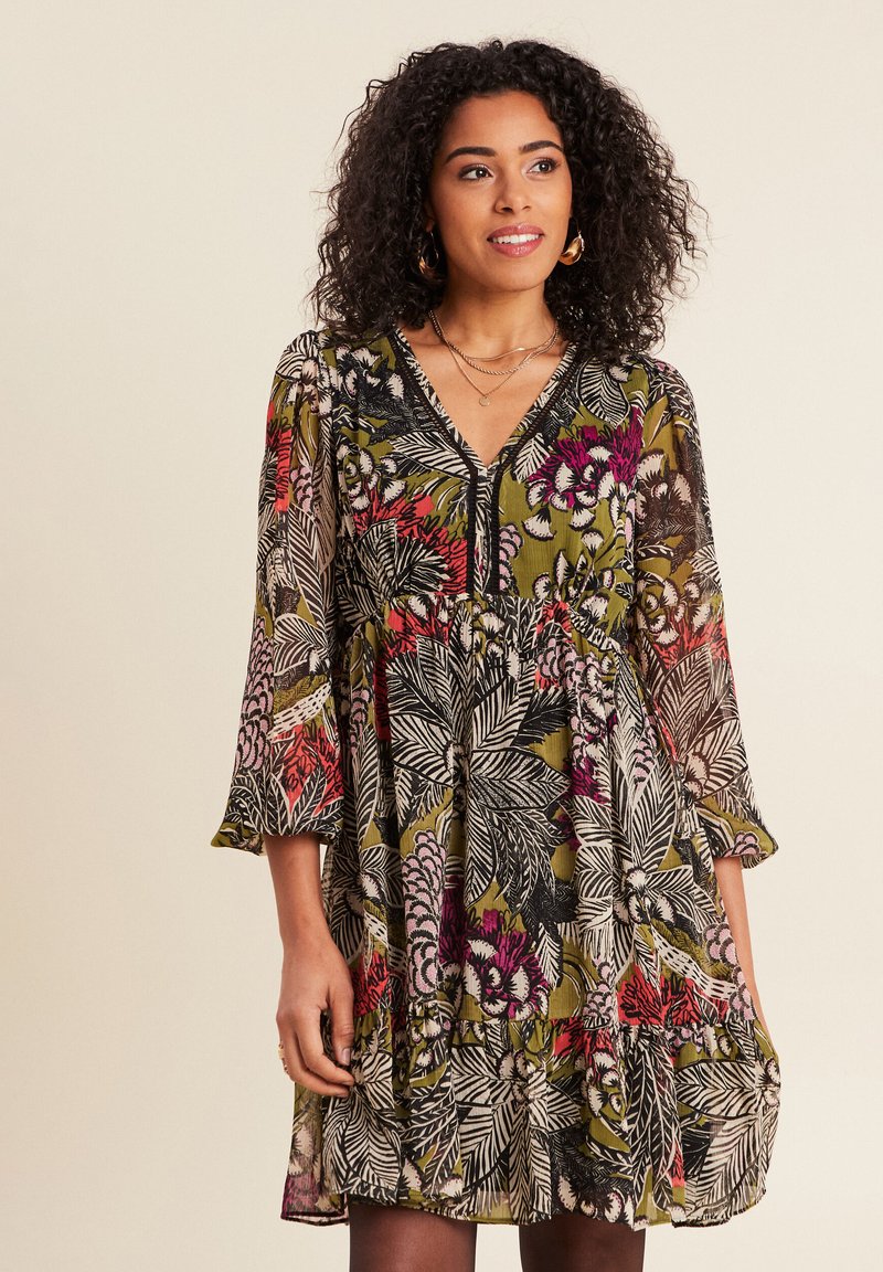 Blumenmusterkleid aus transparentem Stoff, mit dunkelgrünen, pinken und schwarzen Mustern. V-Ausschnitt und Dreiviertelärmel, mit Rüschensaum.