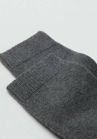 Sivé ponožky z mäkkej tkaniny s rebrovaným lemom. Majú hladkú textúru a zaoblený tvar, vhodné na každodenné nosenie.