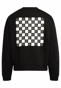Svart genser med rutemønster i hvite firkanter og smilende ansikter. Myk tekstur, klassisk crewneck-design og ribbede mansjetter.