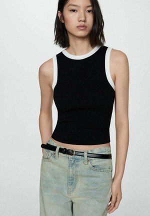 Black ribbed tank top with white trim at the neckline and armholes, paired with light blue high-waisted jeans and a black belt.