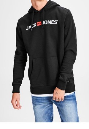 Homme portant un sweat à capuche noir avec le logo "JACK & JONES" en blanc et rouge, assorti à un jean bleu déchiré.