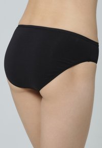 Schwarze Baumwoll-Bikiniunterhosen mit glatter Textur, niedrigem Schnitt und verstärkten Nähten entlang des Bundes und der Beinausschnitte.