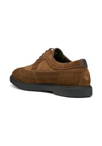 Scarpe stringate in suede marrone con dettagli brogue, punta arrotondata, suola in gomma nera a contrasto e un accento testurizzato sul tacco.