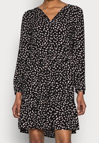 Schwarzes Kleid mit langen Ärmeln, V-Ausschnitt und ausgestelltem Rock. Mit einem rosa Blumendruck und strukturiertem Stoff.