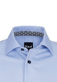 Camicia azzurra chiara con un tessuto texturizzato, dettagli dei bottoni neri e un colletto interno a fantasia nera con piccoli cerchi bianchi.