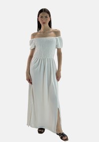 Hvid maxi-kjole med off-the-shoulder design, lavet af letvægtsstof, med smocked buste, korte puffærmer og sideslidser.
