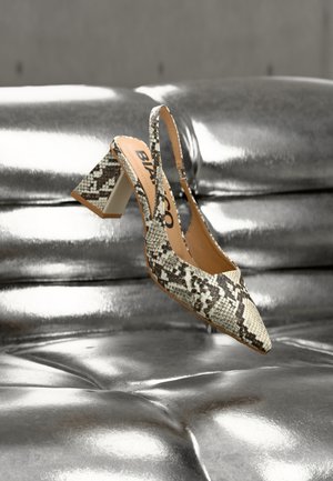 Aukštu kulnu su smailiu priekiu ir tekstūruotu gyvatės odos raštu, su stora balta kulno dalimi, fone atsispindi sidabrinė veidrodinė plokštuma.