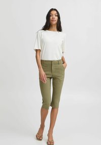Bílý krátký rukáv top spojený se zelenohnědými zkrácenými kalhotami. Tento outfit se vyznačuje jednoduchým designem a lehkým materiálem.