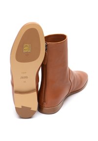 Braune Leder-Ankle-Boots mit einem seitlichen Reißverschluss, runder Zehenpartie und einem niedrigen Blockabsatz. Die Sohle hat goldene Details und Branding.