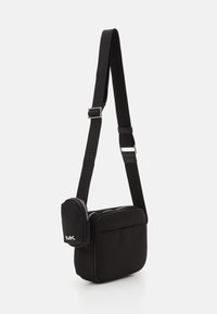 Borsa a tracolla nera in nylon con tracolla regolabile, tasca con zip e accentatura con logo. Design rettangolare elegante con una texture liscia.