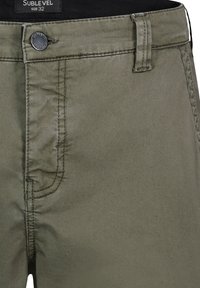 Olive green cotton pants featuring a button closure, belt loops, and front pocket. Smooth texture with subtle stitching details.