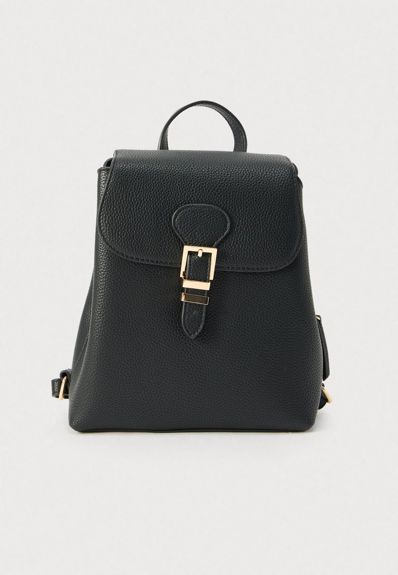 Μαύρο δερμάτινο σακίδιο με υφή φινιρίσματος, εξαρτήματα σε χρυσό τόνο, κούμπωμα με καπάκι, ρυθμιζόμενους ιμάντες και επάνω χερούλι για μεταφορά.