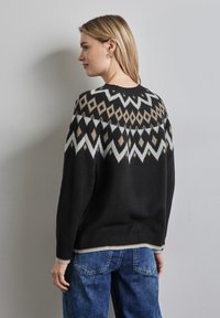 Svart tröja med ett geometriskt mönster i vitt och brunt, med rund halsringning, långa ärmar och ribbade muddar och nederkant.