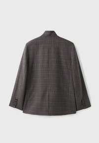 Blazer à carreaux gris foncé vu de dos avec des manches longues et quatre boutons sur chaque poignet, posé à plat sur un fond clair.