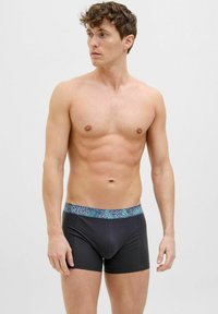 Black boxer briefs with a patterned elastic waistband featuring "JACK & JONES" text and a tropical design. Soft, stretchable fabric.